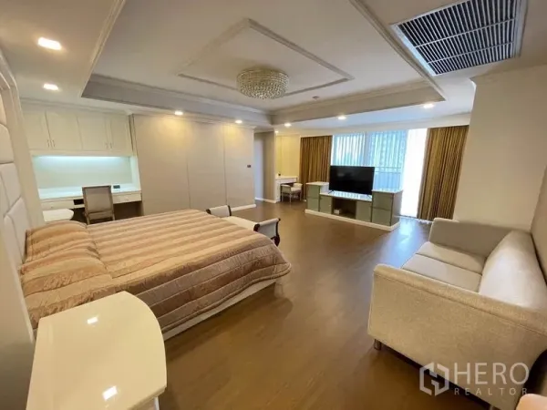 公寓 出租在Watthana, Bangkok - 主卧，特大床、沙发、书桌与靠窗电视柜。