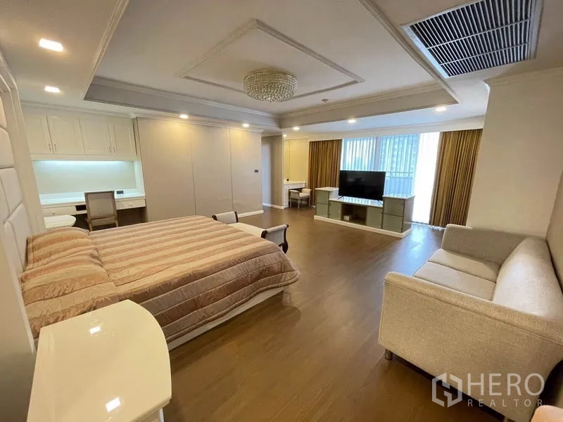 公寓 出租在Watthana, Bangkok - 主卧，特大床、沙发、书桌与靠窗电视柜。