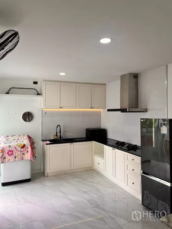 独立式住宅 出租在Lat Krabang, Bangkok - L形厨房，白色橱柜、燃气灶、抽油烟机与黑色台面。