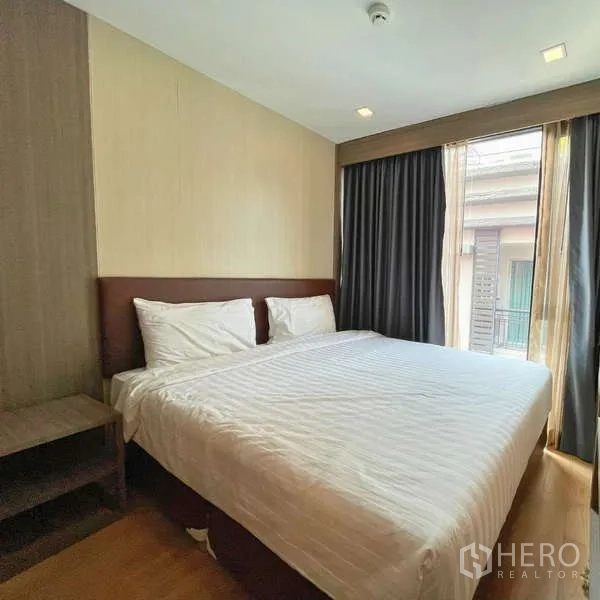 Condominium for rent - Corner bedroom with large windows, blackout curtains and a double bed.