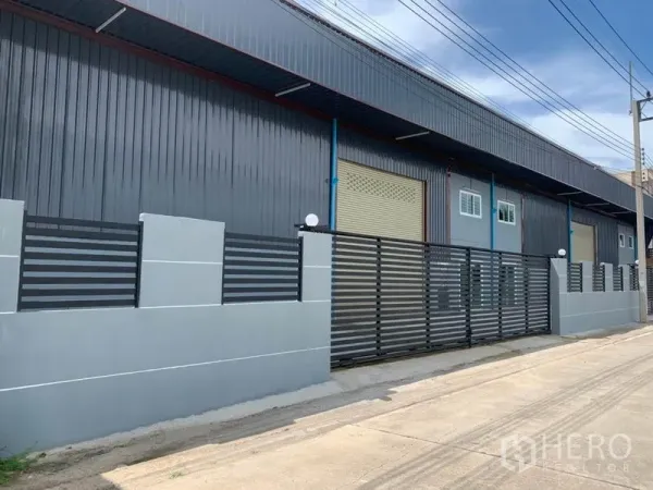 Factory for rent in Khlong Luang, Pathum Thani - Street-facing industrial facade with large roller door, windows and sliding gate.
