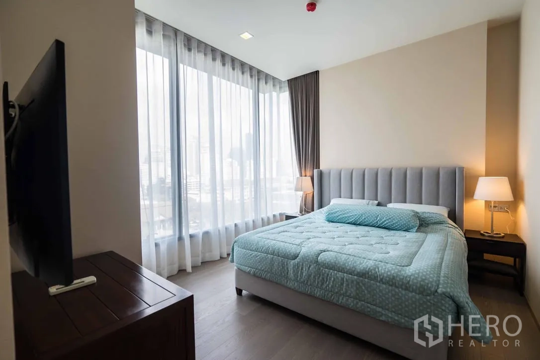 公寓 出租在Watthana, Bangkok - 主卧配软包床、床头灯与环景落地窗。