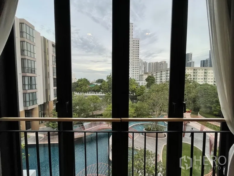 公寓 出租在Watthana, Bangkok - 窗外景观：园林泳池、绿树与周边建筑。