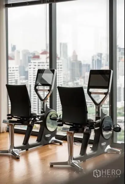 Condominium for rent or sale in Watthana, Bangkok - Close-up of recumbent exercise bikes beside floor-to-ceiling windows.