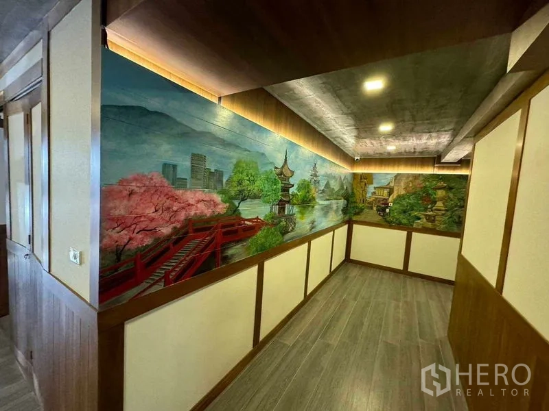 Shophouse for rent in Watthana, Bangkok - Hallway of shophouse with wood paneling, recessed lights and a colorful landscape mural.