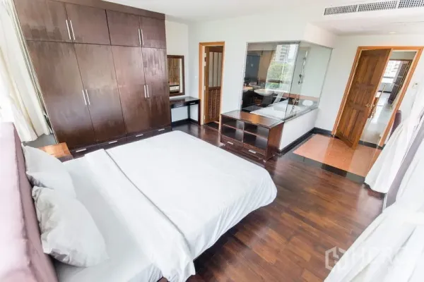 Apartment for rent in Sathon, Bangkok - Master bedroom with large wardrobes, wood floors and a glass-walled ensuite bathroom.