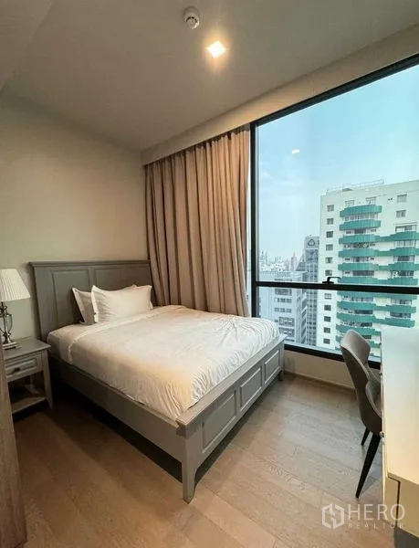คอนโด ให้เช่าในWatthana, Bangkok - ห้องนอนแขก เตียงขนาดมาตรฐาน โต๊ะทำงาน และหน้าต่างบานใหญ่ชมตึกโดยรอบ.