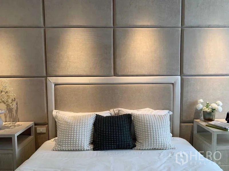 Condominium for rent or sale in Watthana, Bangkok - Close-up of padded headboard, decorative pillows and bedside tables with flowers.