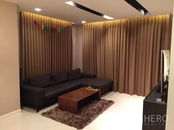 Detached House for rent or sale in Khlong Toei, Bangkok - Cozy living room with L-shaped dark sofa, shag rug, coffee table and full-height curtains with recessed lights.