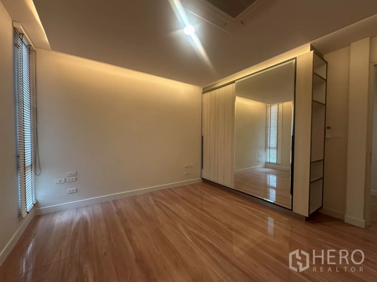 联排别墅 出租在Watthana, Bangkok - 卧室木地板，带镜面推拉衣柜与氛围灯。