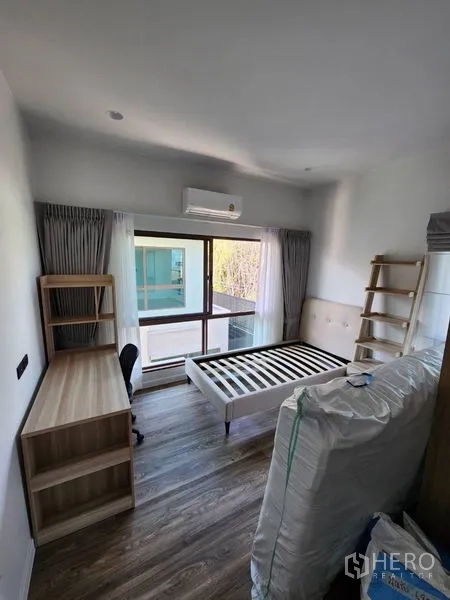 Detached House for rent in Bang Kapi, Bangkok - Bedroom with bedframe, desk and shelving by a large window and sliding door.