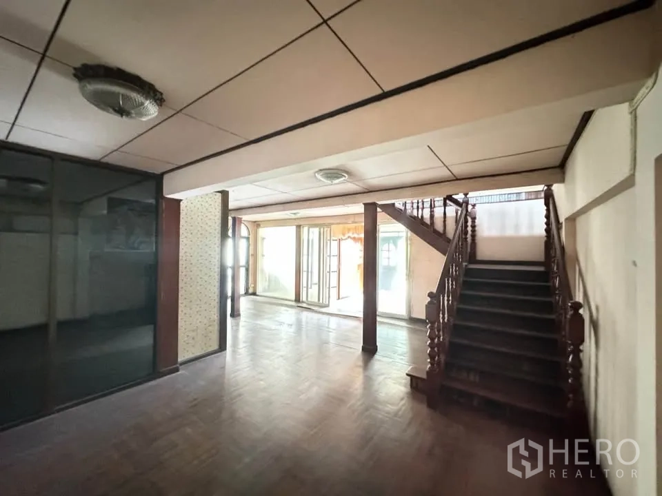 Detached House for rent or sale in Watthana, Bangkok - Ground-floor hall with glass partition and wooden stairs, light from front.