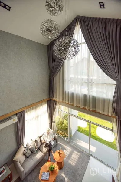Detached House for sale in Lam Luk Ka, Pathum Thani - Loft-style living area viewed from above with tall curtains and pendant lights.