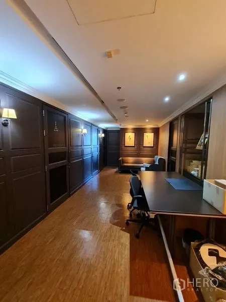 Office Space for rent - Long workspace hallway with built-in desk, recessed ceiling lights and wood floors.