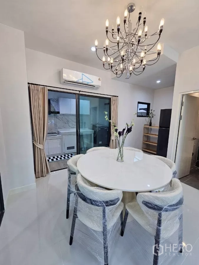 Townhouse for rent in Saphan Sung, Bangkok - Dining area view toward the kitchen with chandelier and air conditioning.