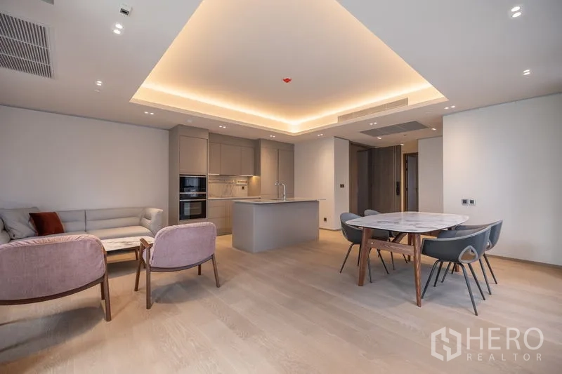 Condominium for rent in Pathum Wan, Bangkok - Spacious layout featuring island kitchen, dining set and lounge seating.