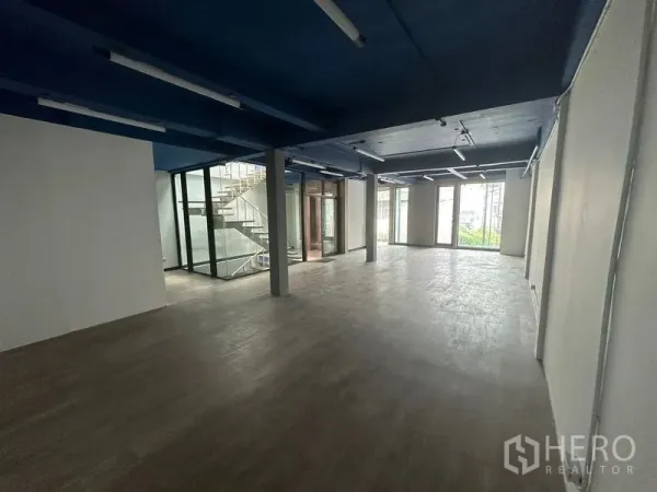 办公空间 出租在Watthana, Bangkok - 长条形开放办公区，配大窗与玻璃楼梯围合。