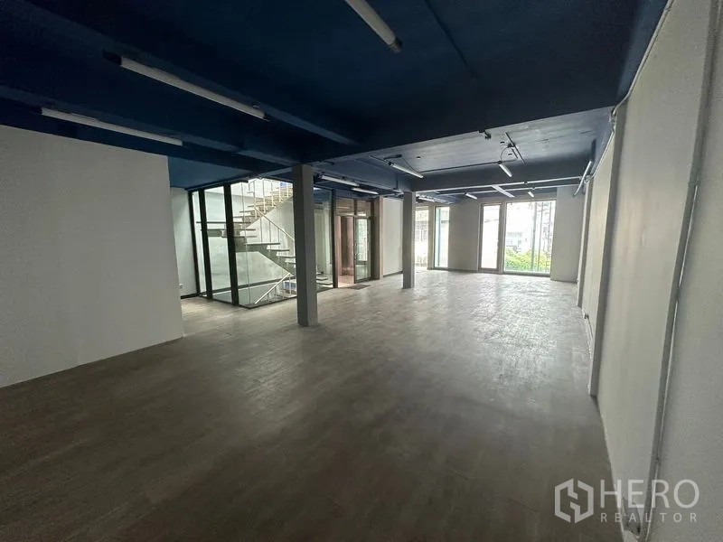 办公空间 出租在Watthana, Bangkok - 长条形开放办公区，配大窗与玻璃楼梯围合。