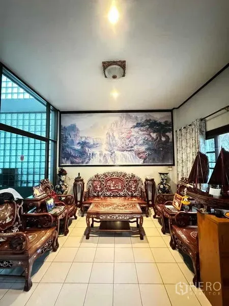 Detached House for sale in Yan Nawa, Bangkok - Bright living room with carved wooden sofa set, tiled floors and large landscape artwork.