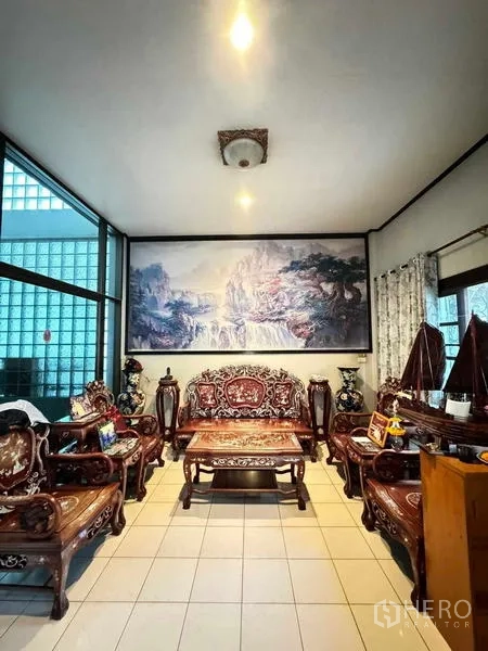 Detached House for sale in Yan Nawa, Bangkok - Bright living room with carved wooden sofa set, tiled floors and large landscape artwork.