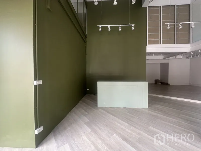 Retail Space for rent in Khlong Toei, Bangkok - Close view of olive-green wall with counter and ceiling track lights in the retail space.