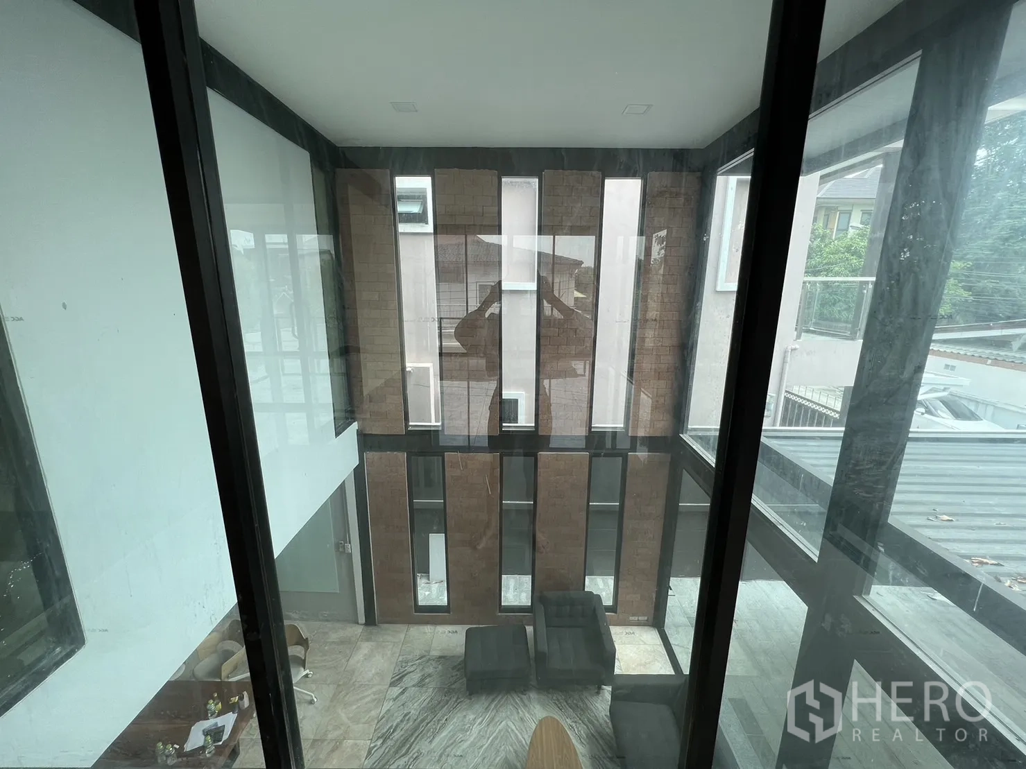 Detached House for rent or sale in Phra Khanong, Bangkok - View from upstairs across the double-height living room and brick feature wall.