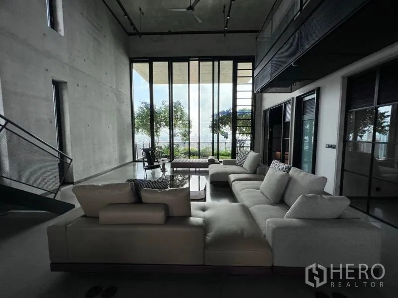 Condominium for rent in Sathon, Bangkok - Loft living area with panoramic windows opening to greenery and city views.