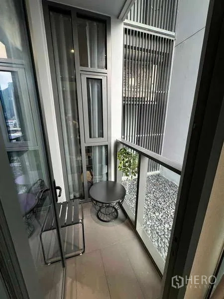 Condominium for rent in Bang Rak, Bangkok - Compact balcony with chair and side table facing architectural screens