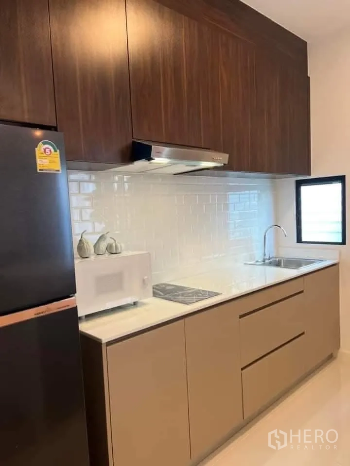 Townhouse for rent in Bang Phli, Samut Prakan - Fitted kitchen with upper cabinets, cooktop, sink, and refrigerator.