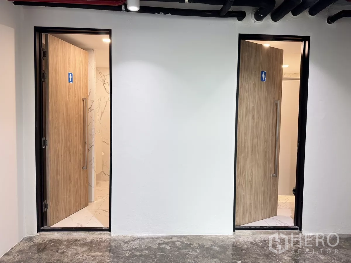 Office Space for rent in Din Daeng, Bangkok - Separate male and female restroom entrances with wood doors and marble-effect tiles inside.