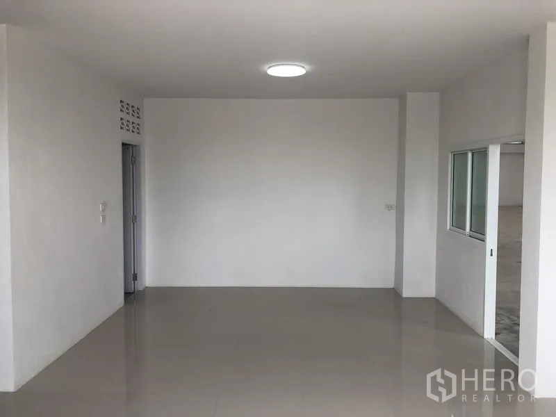 Factory for rent in Sai Noi, Nonthaburi - Open-plan office area with glossy tiles and ceiling light next to a sliding window to the warehouse.