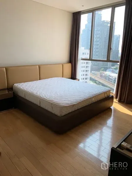 公寓 出租在Watthana, Bangkok - 第二卧室带转角窗与大床，俯瞰都市景色。