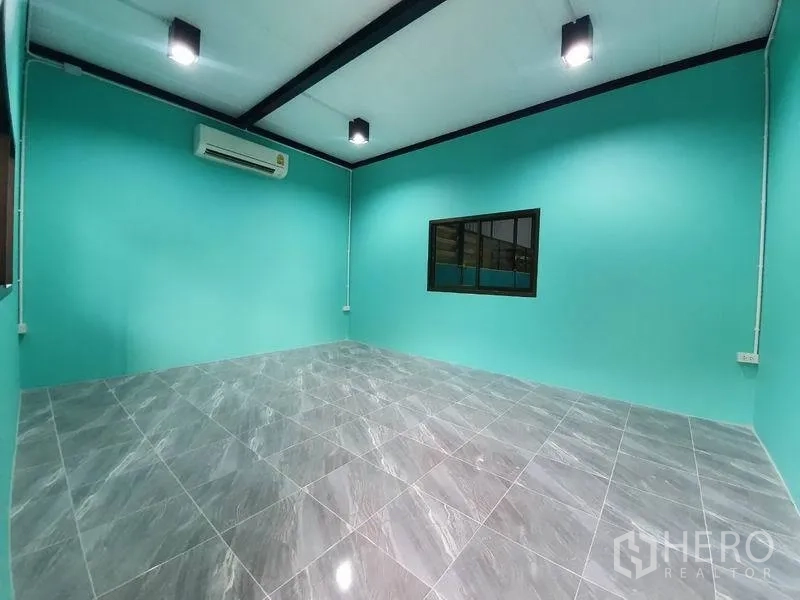 คลังสินค้า ให้เช่าในNonthaburi - ห้องออฟฟิศติดแอร์ ผนังสีฟ้า พื้นกระเบื้องเงา สีเทา และช่องหน้าต่างมองเข้าโกดัง