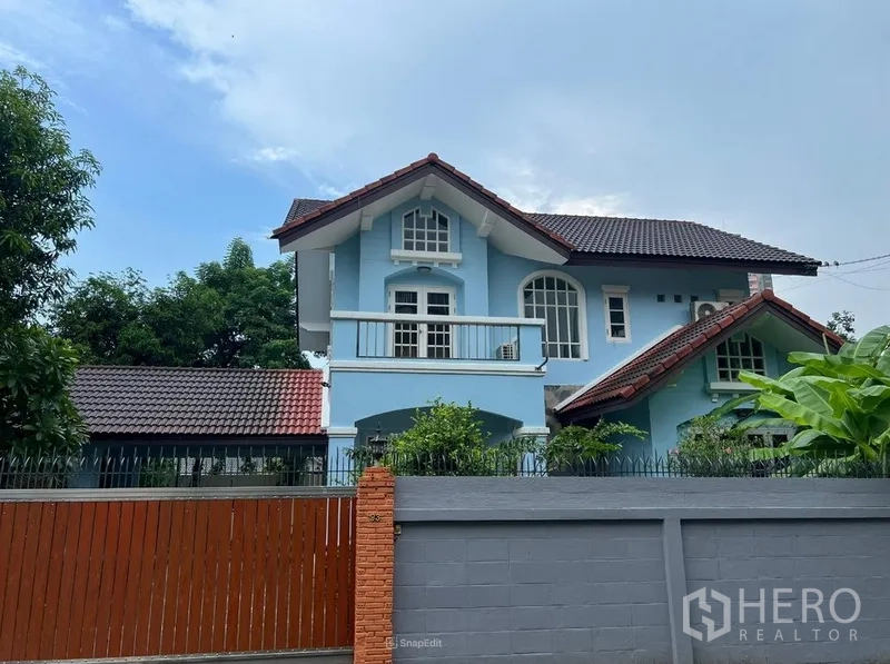 บ้าน ให้เช่าในBang Na, Bangkok - ภาพระยะใกล้ตัวบ้านสีฟ้าสองชั้นพร้อมระเบียงและหน้าต่างโค้ง