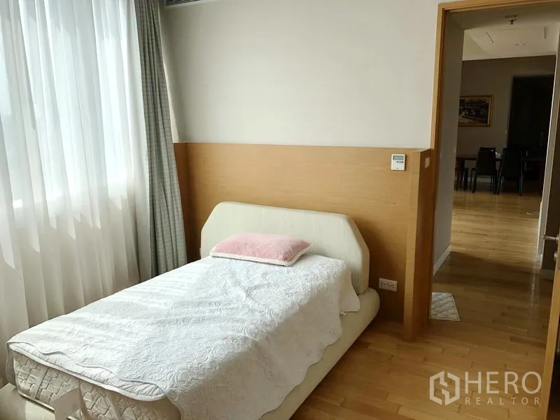 Condominium for rent in Khlong Toei, Bangkok - Sunlit second bedroom with a single bed beside a large curtained window.