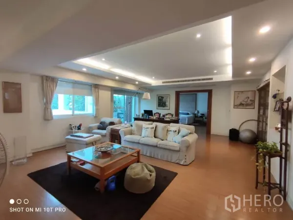 公寓 出租在Watthana, Bangkok - 宽敞客厅，木地板、筒灯天花，配沙发与大窗户