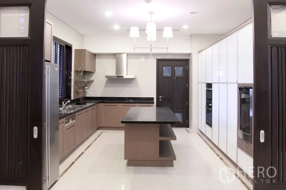 Detached House for rent in Khlong Toei, Bangkok - Fully fitted kitchen featuring an island, stone countertops, built-in ovens and ample cabinetry.