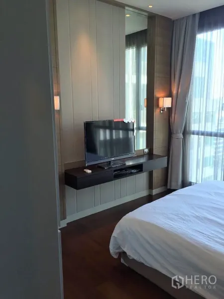 คอนโด ให้เช่าในWatthana, Bangkok - ห้องนอนอบอุ่น หน้าต่างบานใหญ่ เตียงปูผ้าขาว และทีวีติดผนังบนชั้นลอย