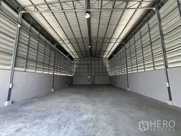Warehouse for rent in Prawet, Bangkok - Empty warehouse hall showing durable concrete floor, high ceiling and large entrance door.