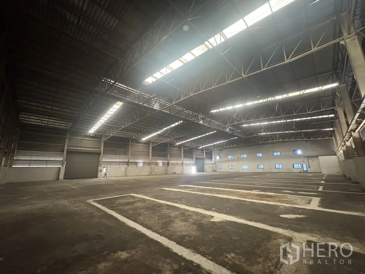 Factory for rent or sale in Samut Prakan - Warehouse interior looking toward the office wall with rows of windows.