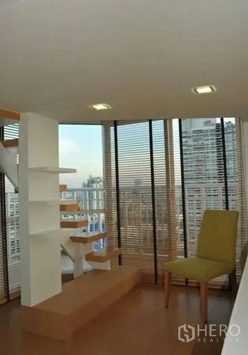 公寓 出租或出售在Watthana, Bangkok - 角落落地窗配木质阶梯与置物架、百叶帘，眺望城市天际线。