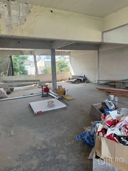 Shophouse for rent in Watthana, Bangkok - Open-plan upper floor in shell condition with concrete floors, beams and renovation materials.
