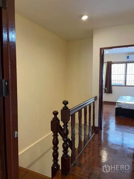Townhouse for rent in Bang Na, Bangkok - Upstairs landing with wooden handrail leading to the two bedrooms.