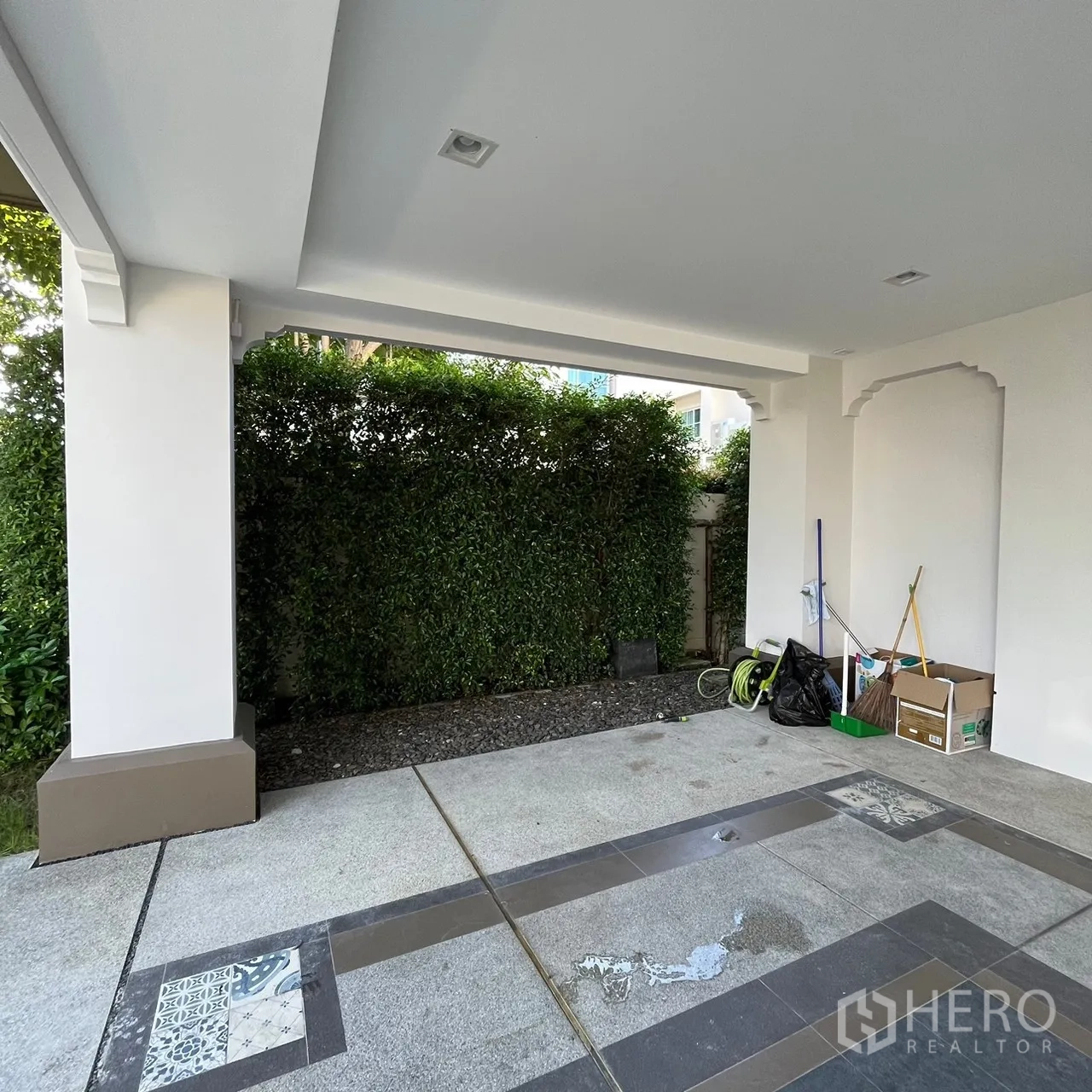 Detached House for rent or sale in Bang Khen, Bangkok - Covered parking area bordered by tall green hedges.