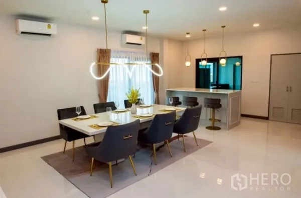 独立式住宅 出租在Bang Phli, Samut Prakan - 明亮餐厅，六人餐桌与金色吊灯，旁有吧台。