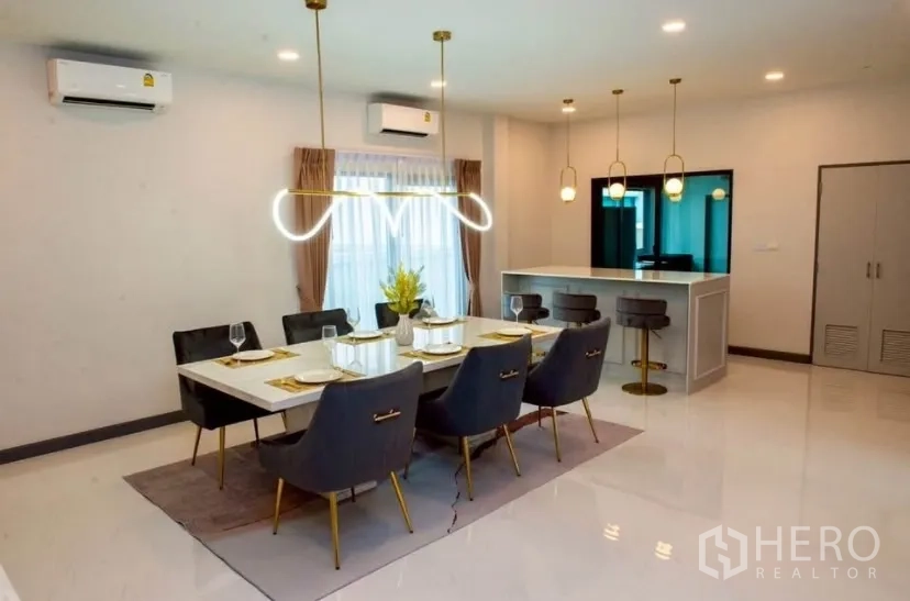 独立式住宅 出租在Bang Phli, Samut Prakan - 明亮餐厅，六人餐桌与金色吊灯，旁有吧台。