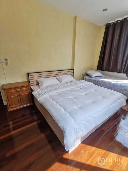 Townhouse for rent in Chatuchak, Bangkok - Bedroom with double bed, bedside cabinet and extra single bed by the window.