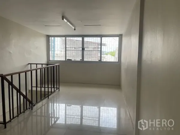 Shophouse for rent in Phra Khanong, Bangkok - Bright mezzanine area with large window and stair balustrade.
