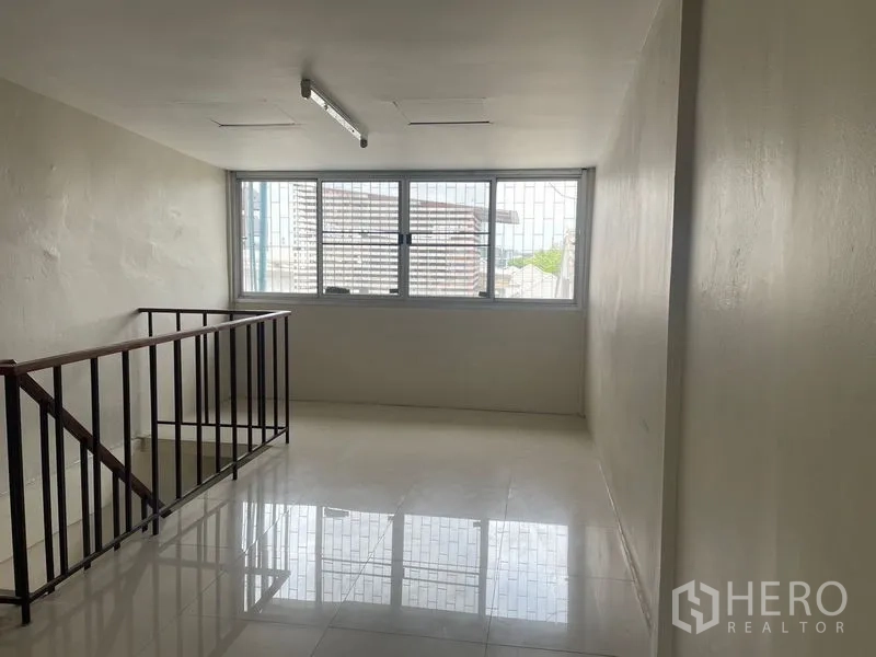 Shophouse for rent in Phra Khanong, Bangkok - Bright mezzanine area with large window and stair balustrade.