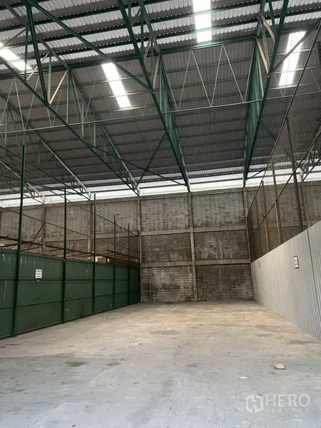Warehouse for rent in Prawet, Bangkok - High-ceiling warehouse bay with skylights, green steel framing and partitioned storage.
